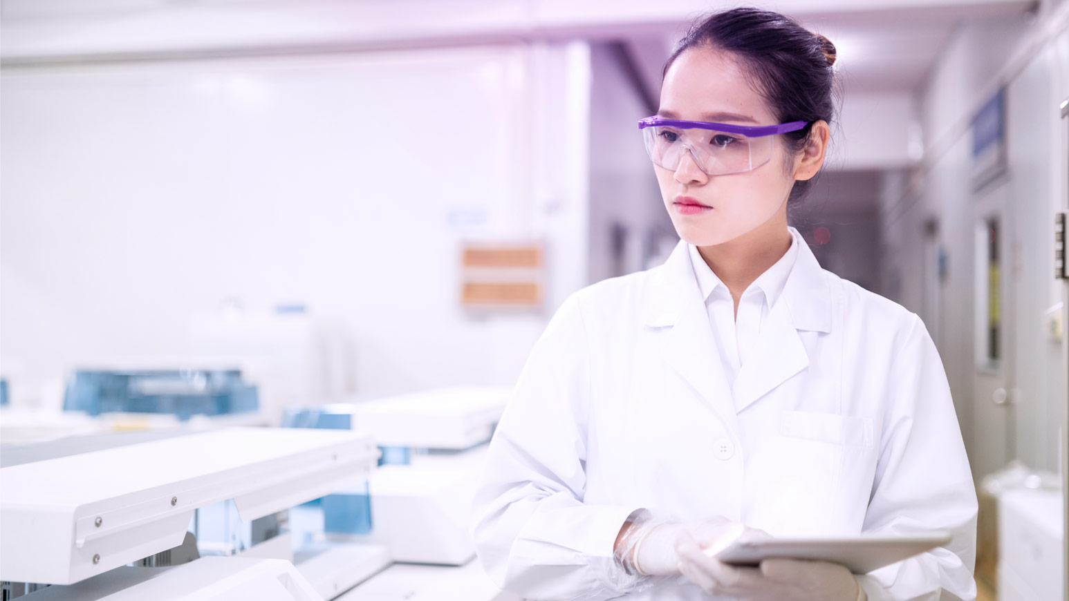 Female scientist in lab coat and goggles holding tablet, featured in Viatris impact section on sustainable healthcare.