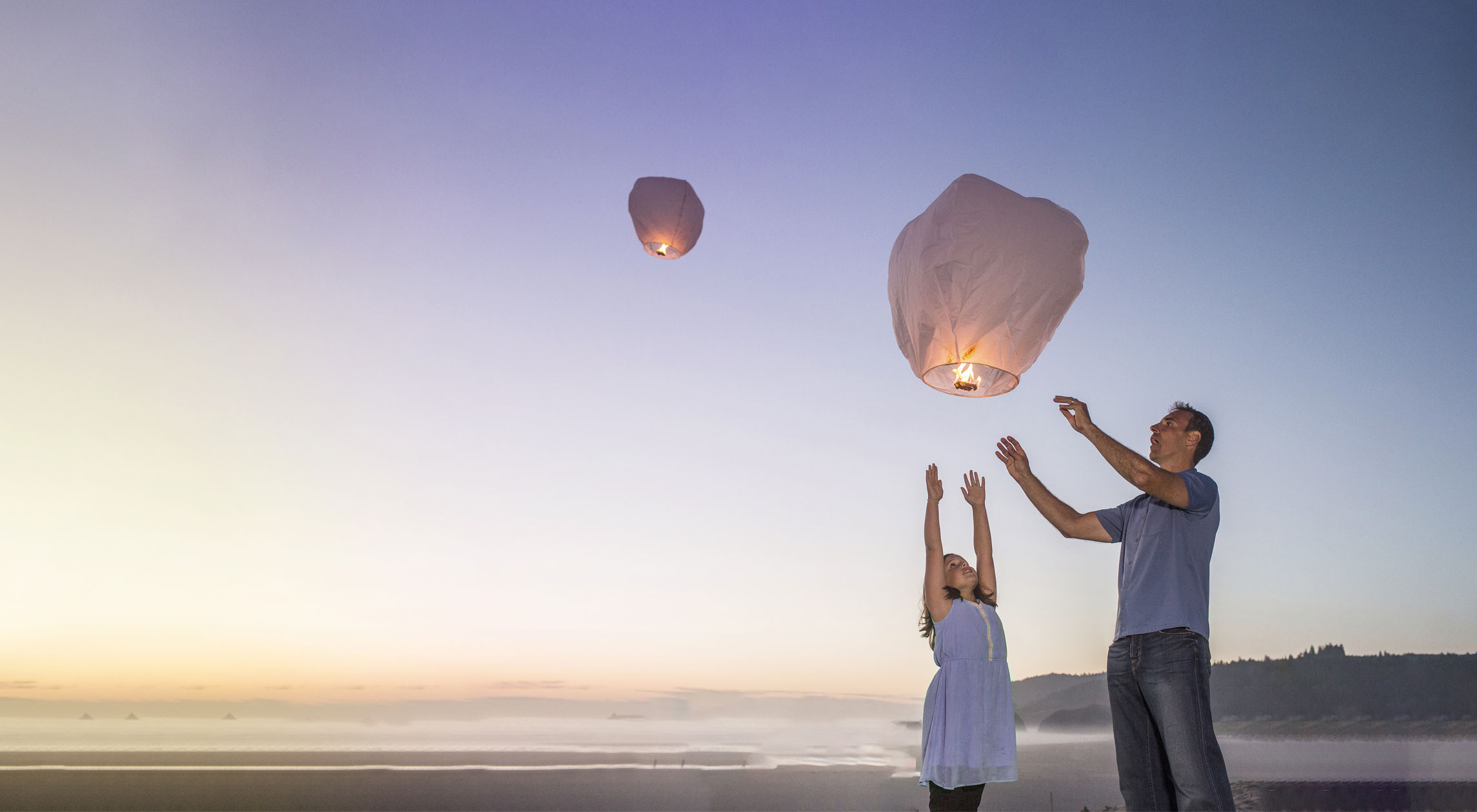 Parent and child releasing sky lanterns at sunset, featured in Viatris careers section promoting purpose-driven work.