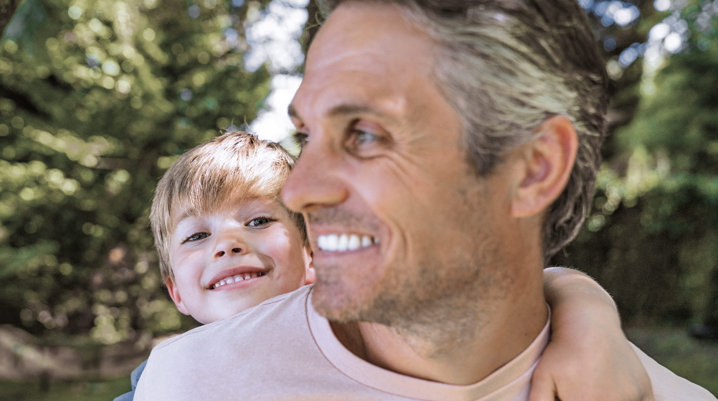 Smiling father carrying child outdoors, featured in Viatris Norway pharmaceutical facts.
